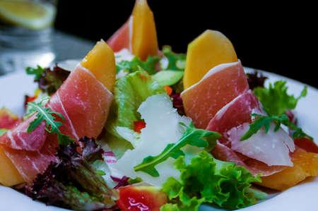 Parma ham served on melon topped with rucola の写真素材