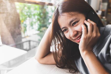 asian women are happy to talk to mobile phones in coffee shopsの写真素材