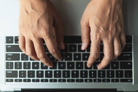 Close up hands typing a button on the laptop, top view