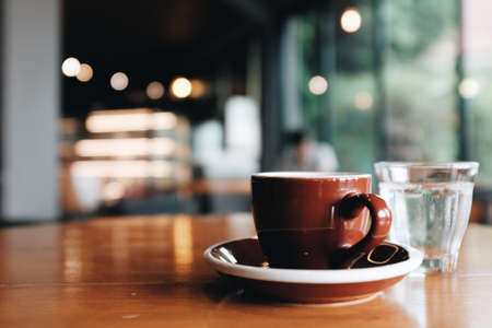 Close-up of a man's hand looking at a stock via his smartphone And there is an espresso coffee beside In a coffee shopの写真素材