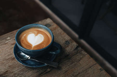Close up of a latte coffee on a wooden table in a coffee shop and copy space
