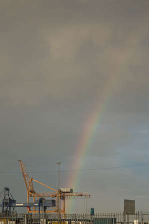 A rainbow abow the crains of a port.の写真素材