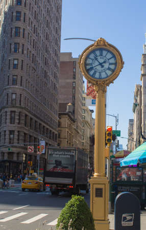 A clock in front of the flat iron building in New York Cityの写真素材