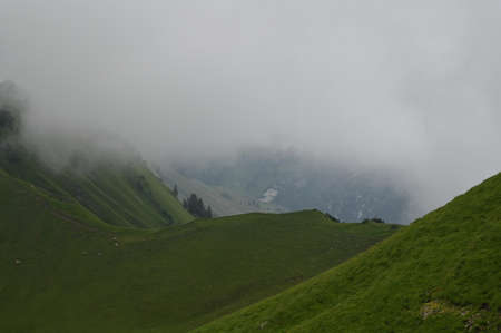 Swiss rural area with green hills on a foggy and cloudy day.の写真素材