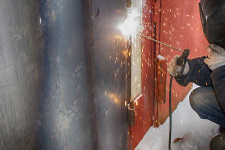 welding a man repairs a garage outdoors