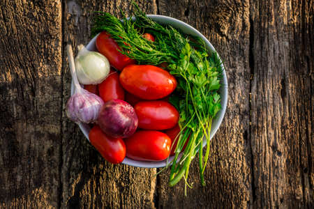 ripe tomatoes in bowl on wooden backgroundの写真素材