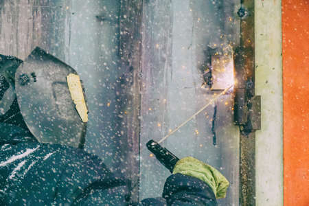 welding a man repairs a garage outdoors