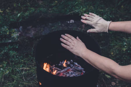 hands warming themselves by a barrel fire with homeless people socialの写真素材