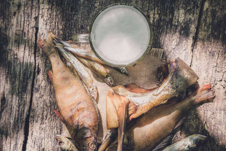 glass of beer with dried fish on wooden background in rustic styleの写真素材