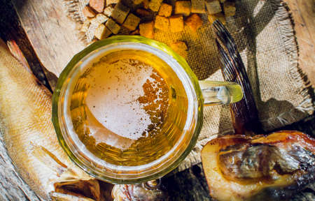 glass of beer with dried fish on wooden background in rustic style