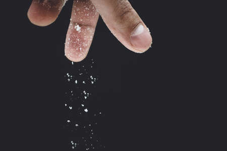 seasoning salt cooking on black background closeup male handの写真素材