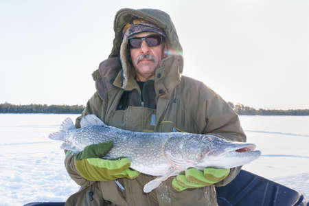 man holding catch winter fishing pike fish