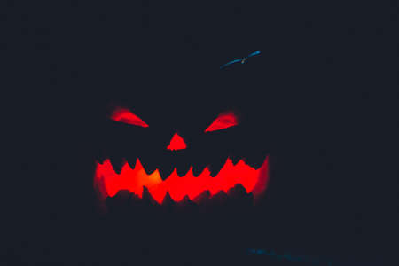 scary Halloween pumpkin on black background. holiday autumn intimidating silhouette selective focus...