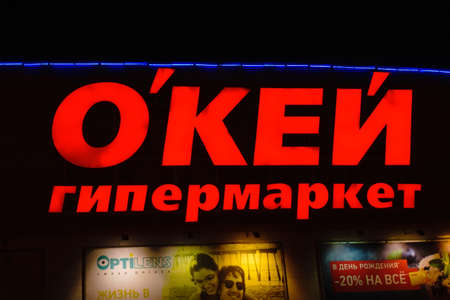 Tyumen, Russia - October 03, 2019: Signboard of the name folded from large red letters above the entrance to the store hypermarket Okay. Night photographyのeditorial素材