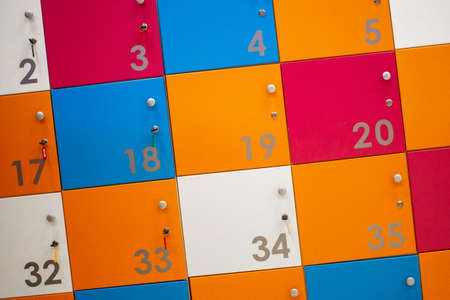 Luggage storage for things. Cells in white, orange, red, blue with metal handles and locks. Cells numbered with metal numbers. Temporary storage of things.の写真素材