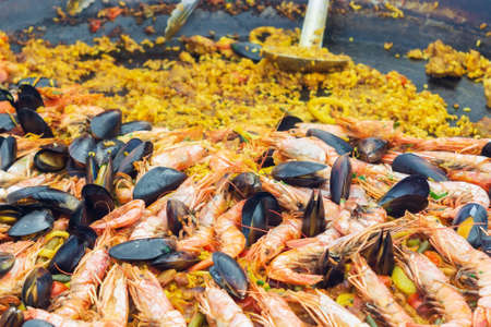 Spanish dish paella closeup cooking. national dish rice with seafood. Paella traditional Spanish food, seafood paella in the fry pan with mussels, king prawns, langoustine and squids.の写真素材