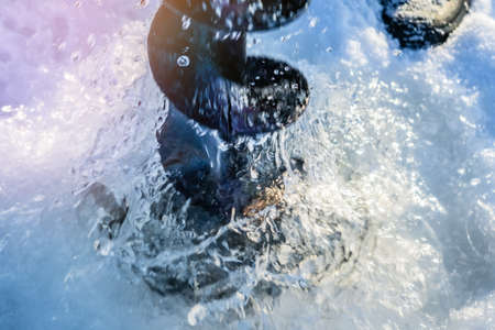 drills a hole in the ice. Winter fishing on the background of a frozen lake.の写真素材