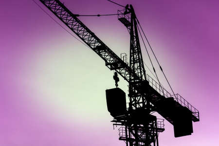 silhouette of metal crane used in construction crane close-up. on the purple background of the sunset skyの写真素材