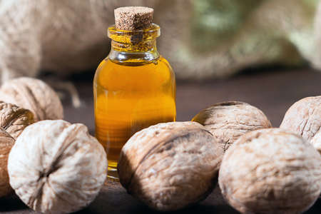 Walnut oil in glass of bottle, on wooden background. healthy food for brain. Fresh walnuts background nut conceptの写真素材