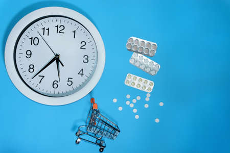 tablets and watches on a blue background, the concept of buying and taking pills and medicines.の写真素材
