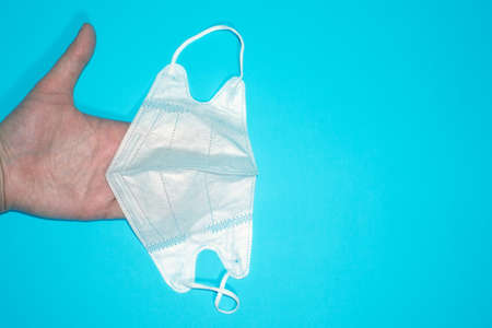 medical mask on a blue background in his hand. the view from the top, Feat lay. medical concept. space for text, copy spaceの写真素材