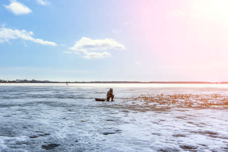 Winter fishing. Ice fisherman fishing on the lake in the cold winther dayの写真素材