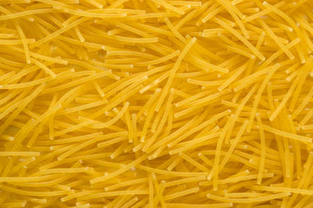 short thin vermicelli on the whole background. texture of dry yellow pasta.