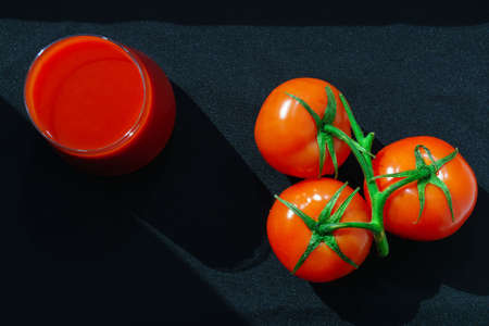 tomatoes and tomato juice in glass. Vegetable drink on a black background. Healthy healthy product, dietaryの写真素材