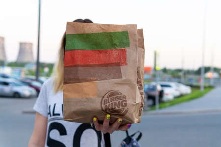 Tyumen, Russia-June 09, 2020: food in the hand of a girl from the fast food restaurant Burger kingのeditorial素材