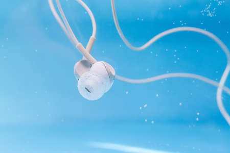 headphones listening to music in the water, under the water in the pool. waterproof equipmentの写真素材