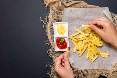 fries-fried potatoes with cheese sauce, ketchup on a black background with cheese sauce. vertical...
