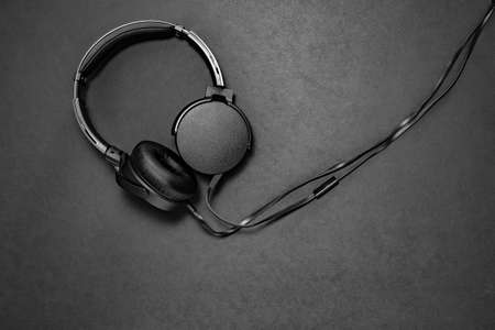 Black headphones on black matte background. Minimalistic composition topview. space for text, free...