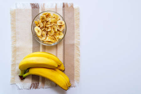 Fresh bananas and the dry banana chips on table. space for textの写真素材