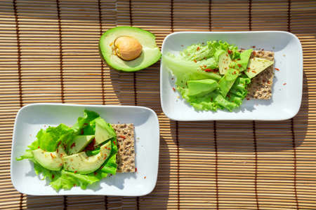 Snack from wholegrain rye crispbread cracker with avocado and salad. Conception of healthy eating.