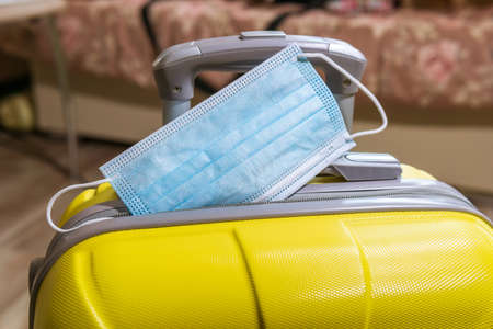 Suitcase with face mask. Preparing for trip abroad after corona virus pandemic. Travel concept.の写真素材