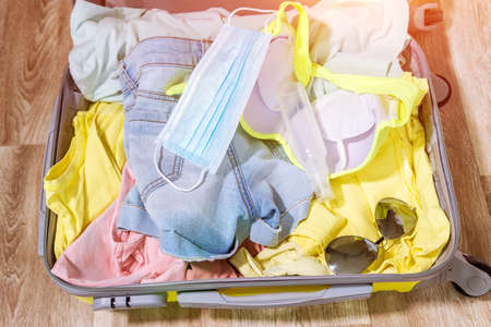 suitcase with protective white mask, clothes, hand sanitizer gel. New traveling life Coronavirus quarantine.の写真素材