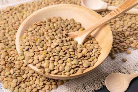 Dry brown lentils in a wooden bowl on the table close-up. rustic