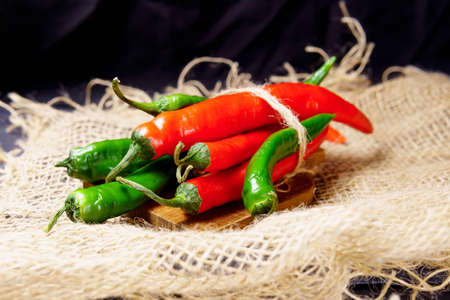 Red pepper and green, on dark wooden board, selective focus. Organic food concept.の写真素材
