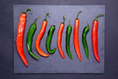 Red and green hot chili peppers with black background. flat lay