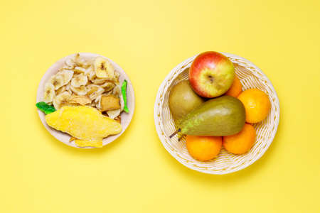 Assortment of dried and raw fruits on a yellow background, healthy food concept