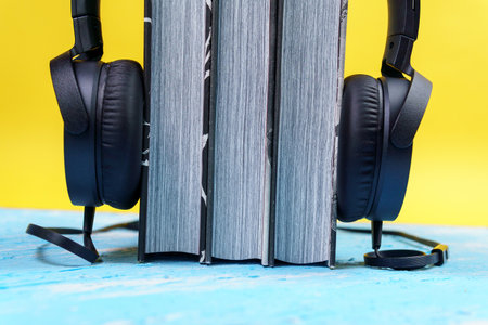 black headphones with a stack of books. The concept of audio books and modern education