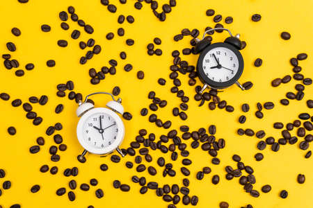 Coffee beans, alarm clock, on yellow background. Creative Concept time to work. Flat lay top view...