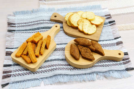 different types of crackers, croutons on wooden boards close-up, white, brown, dark