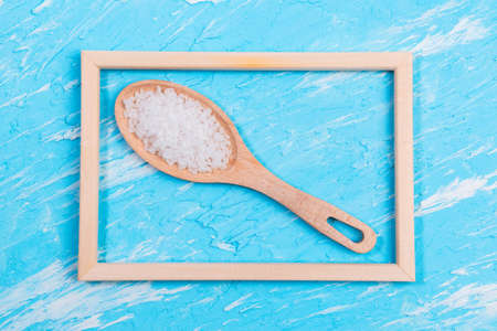 sea salt in a wooden spoon on a blue background with space for copying textの写真素材