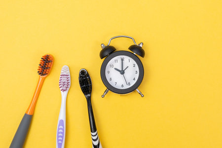 toothbrush and alarm clock time to brush your teeth before going to bed, in the morning on a yellow background.の写真素材