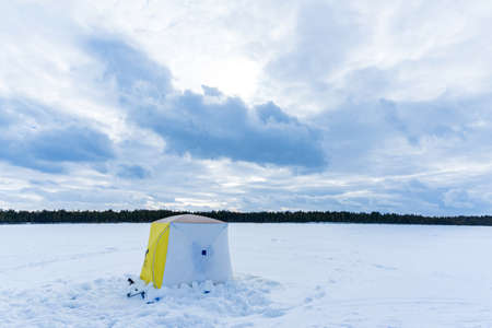 winter tent on the lake for fishing. winter sports space for copying text. fishing equipment