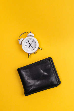 alarm clock and wallet yellow background. Time is money concept. vertical photo