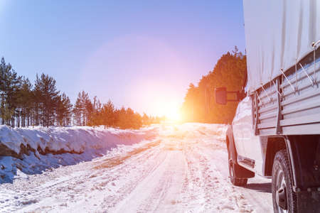 White car on a winter road through a snow covered forest. Bottom view. car on winter snowy road in mountains in sunny day.の写真素材