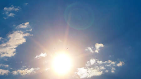 Bright sun against a blue sky with silhouettes of birds. The concept of freedom, space for textの写真素材