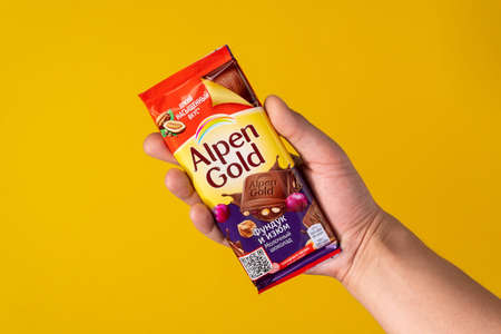 Tyumen, Russia-May 25, 2021: Alpen gold chocolate with hazelnuts and raisins on a yellow backgroundのeditorial素材